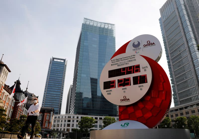 FILE PHOTO: A man wearing a protective mask walks past a countdown clock for the Tokyo 2020 Olympic Games amid the coronavirus disease (COVID-19) outbreak in Tokyo