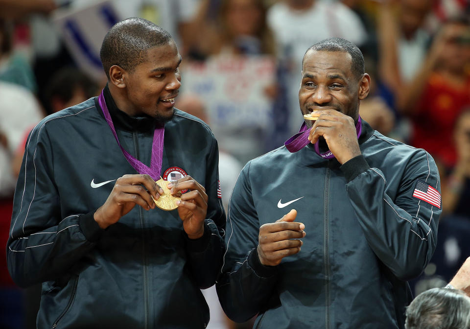 LONDON, ENGLAND - AUGUST 12: Lebron James #6 (R) of United States bites his gold medal after defeating Spain in the Men's Basketball gold medal game on Day 16 of the London 2012 Olympics Games at North Greenwich Arena on August 12, 2012 in London, England.&nbsp;