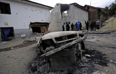 Residents and members of the media talk in front of damaged houses in Kumanovo, Macedonia May 11, 2015. REUTERS/Ognen Teofilovski