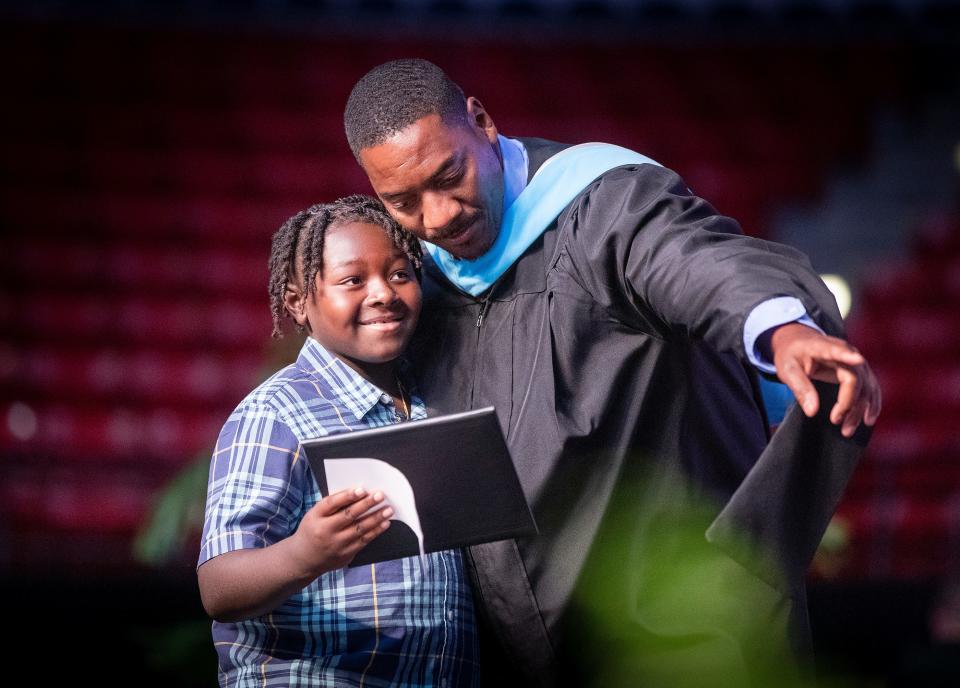 King James Hawthorne ,8,  is directed to the center of the stage by Tenoroc High School Vice Principal Travian Smith as he is presented his late brother , Freddie Hawthorne's diploma during the 2022 Tenoroc High School graduation ceremony at the RP Funding Center in Lakeland Fl. Thursday May 19,  2022. Freddie Hawthorne passed away during the school year and his family was awarded his diploma. ERNST PETERS/ THE LEDGER