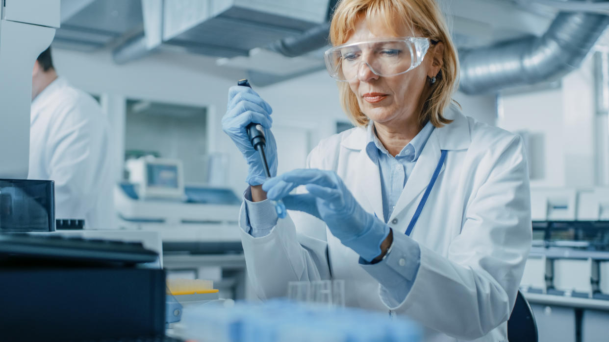 Female Research Scientist Uses Micro Pipette while Working with Test Tubes.