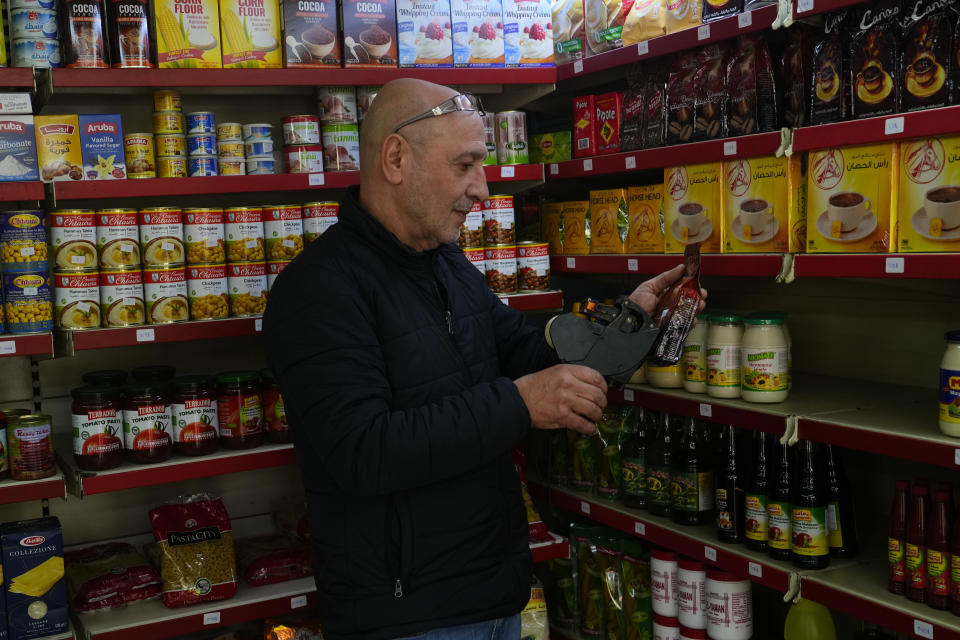 Moheidein Bazazo changes price tags from Lebanese pound to the U.S. dollar in a shop in in Beirut, Lebanon, Wednesday, March 1, 2023. Lebanon began pricing consumer goods in supermarkets in U.S. dollars Wednesday as the value of the Lebanese pound hit new lows. (AP Photo/Hassan Ammar)