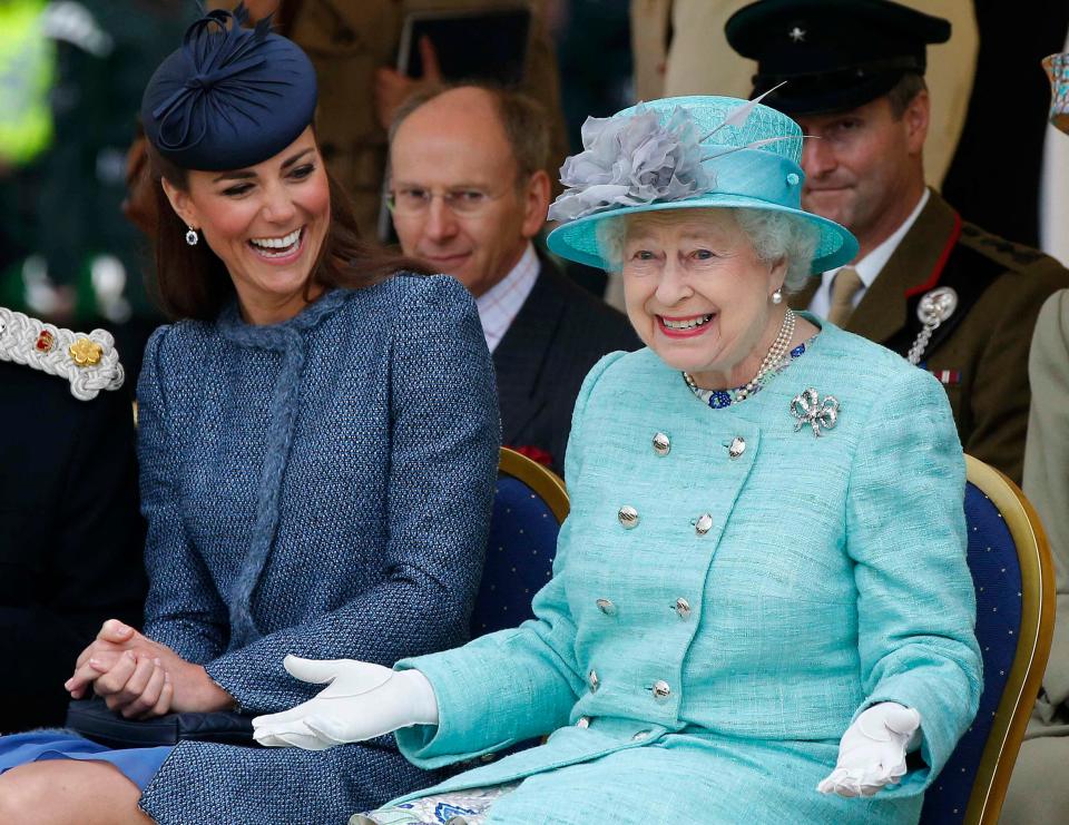 Queen Elizabeth gestures while watching a children's sporting event as Kate Middleton looks at her and laughs