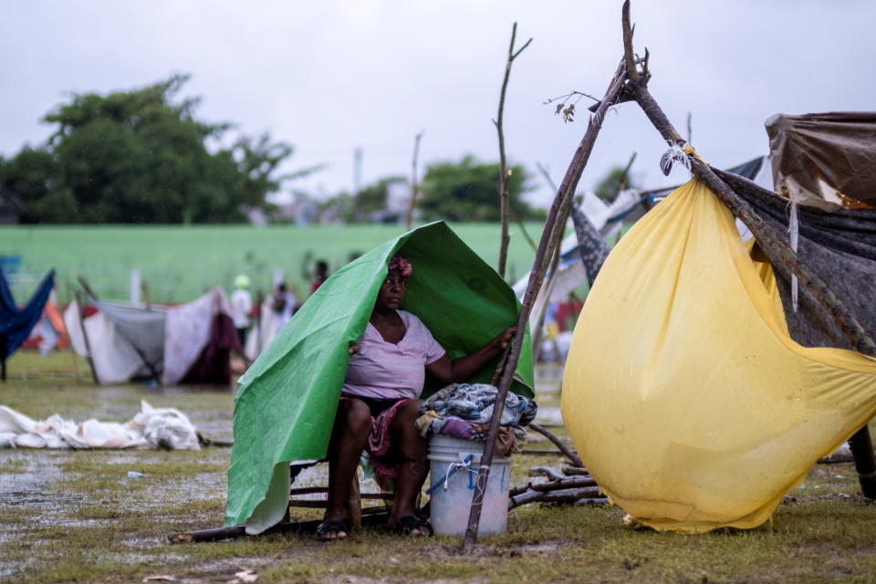 A woman shelters from the rain under a tarp in a makeshift camp after tropical depression Grace passed through the area following Saturday's 7.2 magnitude quake, in Les Cayes, Haiti August 17, 2021. REUTERS/Ricardo Arduengo