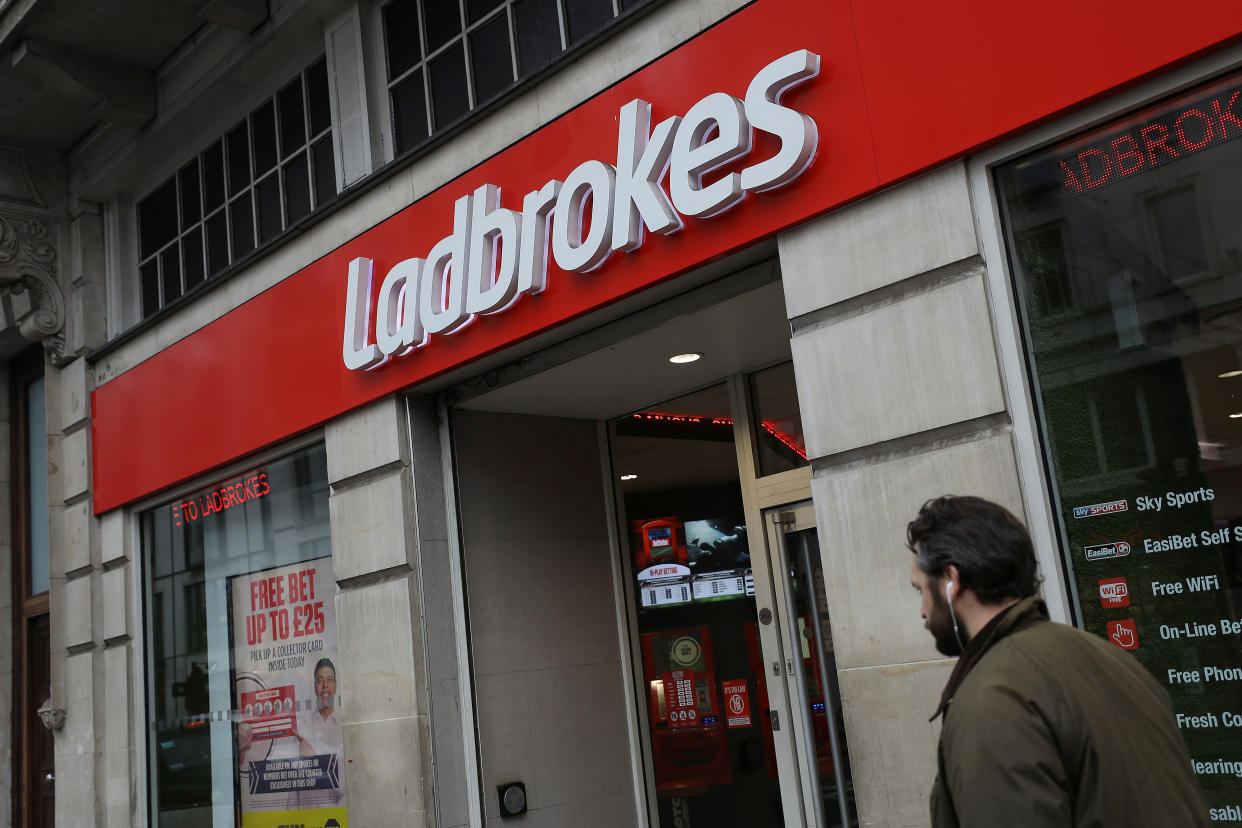 A pedestrian walks past a branch of Ladbrokes in London, which is owned by Entain plc. Photo: Simon Dawson via Reuters.