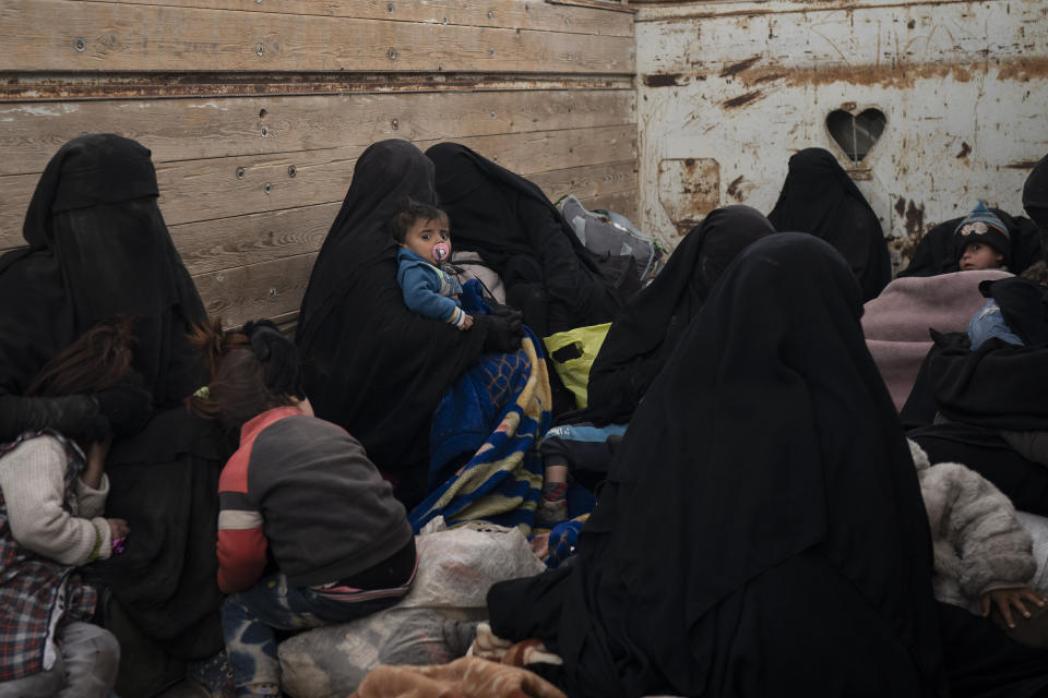 Women and children sit in the back of a truck as they wait to be screened by U.S.-backed Syrian Democratic Forces (SDF) after being evacuated out of the last territory held by Islamic State militants, in the desert outside Baghouz, Syria, Wednesday, Feb. 27, 2019. (AP Photo/Felipe Dana)