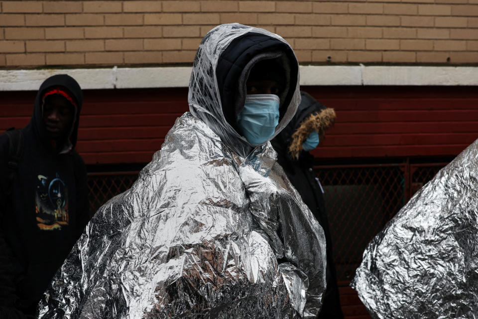 Migrants in thermal blankets wait outside a shelter in the East Village in New York City.