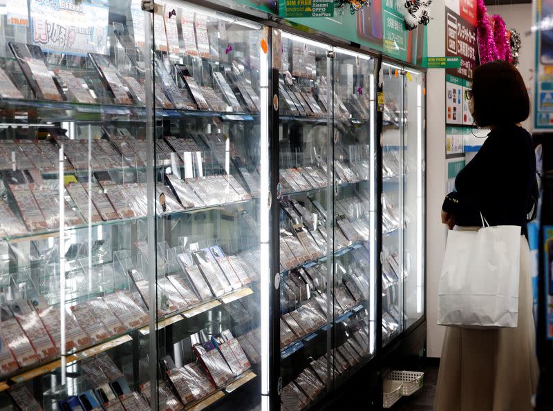 A customer looks at a display of used mobile phones in Iosys Corp's shop selling used smartphones, in Tokyo