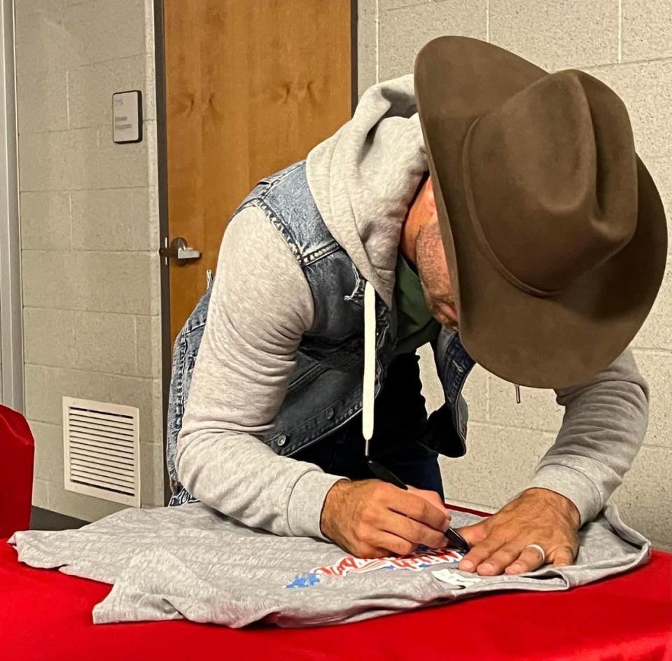 Country music artist Mitch Rossell signs a shirt for a fan during a meet and greet following his November concert at Canton South High School.