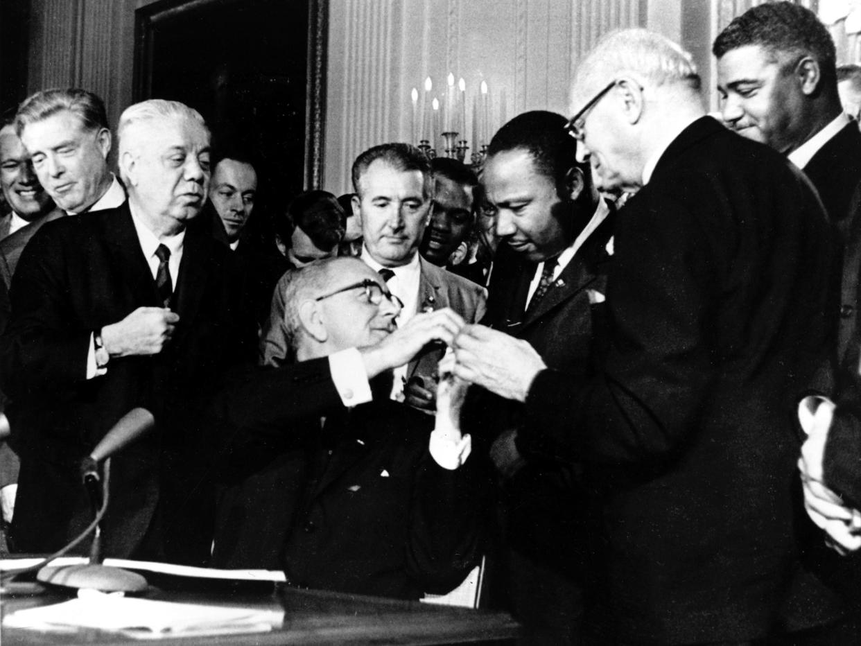 President Lyndon B. Johnson reaches to shake hands with Dr. Martin Luther King Jr. after presenting the civil rights leader with one of the 72 pens used to sign the Civil Rights Act of 1964 in Washington, D.C., on July 2, 1964.