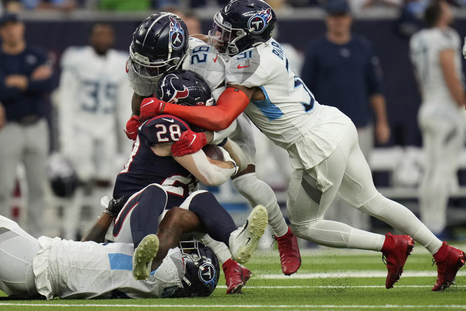 Houston Texans running back Rex Burkhead (28) is stopped by Tennessee Titans cornerback Kristian Fulton (26) and free safety Kevin Byard (31) during the first half of an NFL football game, Sunday, Jan. 9, 2022, in Houston. (AP Photo/Eric Christian Smith)