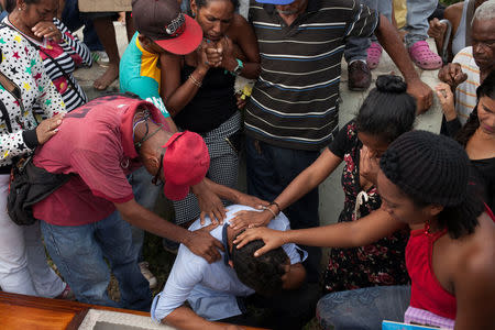 Bernabe Moya reacts over the coffin of his wife Alexandra Conopoy, a pregnant 18 year-old killed during an incident over scarce of pork, according to local media, in Charallave, Venezuela January 1, 2018. Picture taken January 1, 2018. REUTERS/Adriana Loureiro