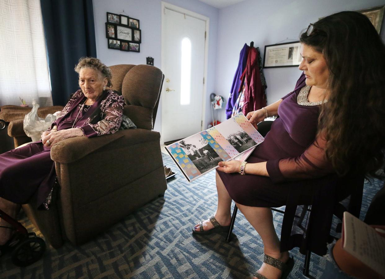 Eva Mae Brown, who turns 93 on Mother's Day, listens to her daughter, Angela Brown as Angela looks through a book of photos from her mother's childhood.