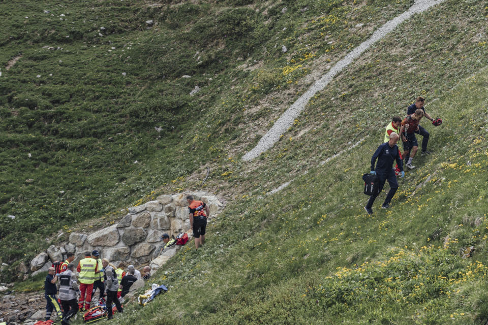 Switzerland's Gino Mader, left, receives medical attention after crashing as Magnus Sheffield of the United States, right, is helped away, during the fifth stage of the Tour de Suisse, Tour of Switzerland cycling race, in Punt, Thursday, June 15, 2023. Swiss cyclist Gino Mader has died one day after crashing and falling down a ravine during a descent at the Tour de Suisse. The Bahrain-Victorious team announced the news. The 26-year-old Mader crashed on a fast downhill road approaching the end of the mountainous fifth stage into La Punt. (SWpix/Zac Williams/Keystone via AP)