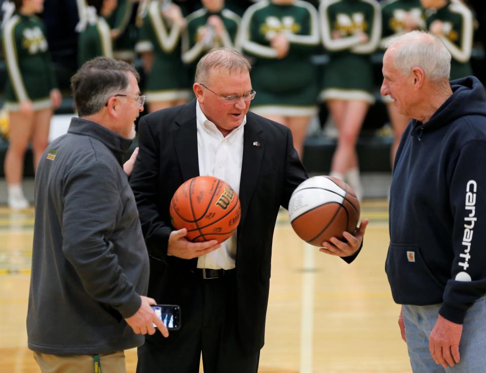 Northeastern head boys' basketball coach Brent Ross (center) receives commemorative basketballs from former coach Tom Zell (right) and Athletic Director Gerry Keesling (left) for becoming the program's all-time wins leader Feb. 17, 2023.