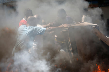 Men pull a street stand out of a burning barricade during a march to demand an investigation into what they say is the alleged misuse of Venezuela-sponsored PetroCaribe funds, in Port-au-Prince, Haiti, October 17, 2018. REUTERS/Andres Martinez Casares