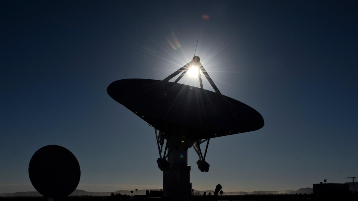  Radio telescopes point upward in the desert under a bright sun. 