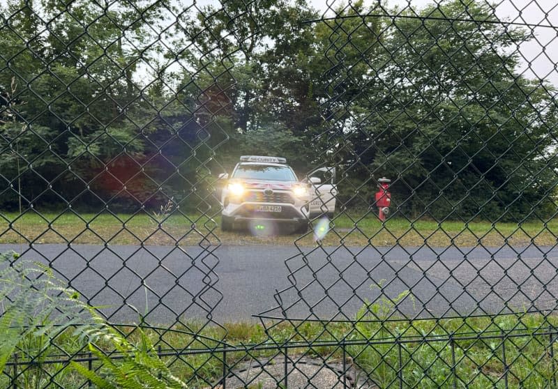 An airport security car at Cologne-Bonn Airport is parked behind the airport fence. The police assume that activists from the Last Generation Climate Initiative have gained access to the airport grounds through the visible hole in the fence. Benjamin Westhoff/dpa