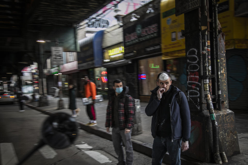 FILE - A man smokes a cigarette while waiting to cross a street in the Brooklyn borough of New York, on Wednesday, March 25, 2020. (AP Photo/Wong Maye-E, File)