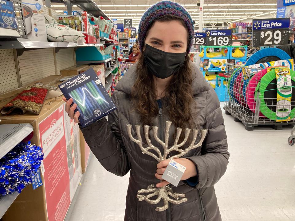 A woman holding a menorah and candles at Walmart.