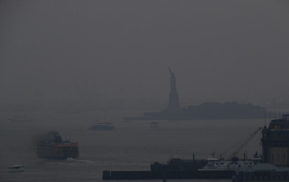 The Staten Island Ferry departs from the Manhattan terminal through a haze of smoke with the Statue of Liberty barely visible, Tuesday, July 20, 2021, in New York. Wildfires in the American West, including one burning in Oregon that's currently the largest in the U.S., are creating hazy skies as far away as New York as the massive infernos spew smoke and ash into the air in columns up to six miles high. (AP Photo/Julie Jacobson)