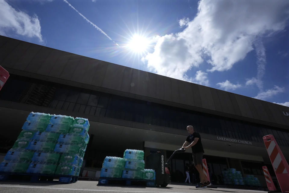 Clayton Hurst moves a pallet of water as he and other staff at Lakewood Church operate a cooling station and water distribution line in Houston, Tuesday, July 9, 2024. The effects of Hurricane Beryl left most in the area without power. (AP Photo/Eric Gay)