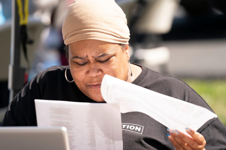 Communication director for Michigan Liberation Marjon Parham looks through a list of names as she helps sign in metro Detroiters hoping to expunge their criminal records Friday, Aug. 12, 2022 at the Center for the Works of Mercy in Detroit.