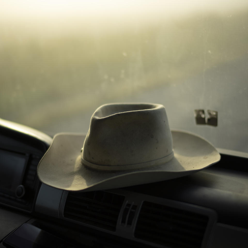 Manadier Jean-Claude Groul's hat sits on the dashboard of his truck as he transports Camargue bulls from one pasture to another in the Camargue, southern France, Oct. 11, 2022. Due to the evolving real estate market and environmental factors, ranchers like Groul are having to breed their animals higher up at the limit of the Camargue Delta, often fracturing their land and forcing them to transport their animals in trucks across separated pastures. (AP Photo/Daniel Cole)