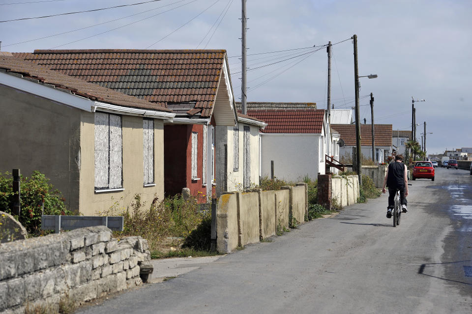 Previously unreleased photo dated 20/08/15 of a man cycling past boarded up properties on Brooklands, on the Brooklands estate, in East Jaywick, near Clacton, Essex, which has been classed as the most deprived neighbourhood in England, according to official statistics.