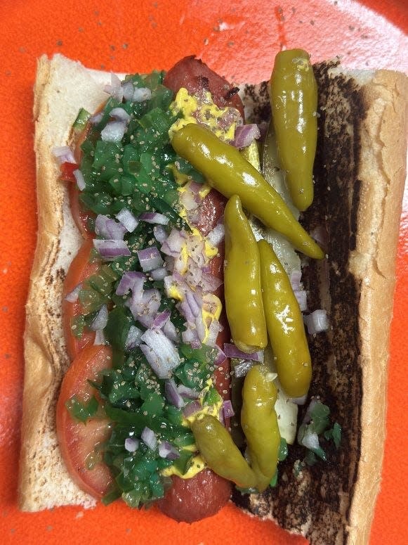 A Chicago Dog with wagyu beef also has sport peppers, tomatoes, onions, relish, mustard and a pickle spear. This one is on a poppy seed bun.
