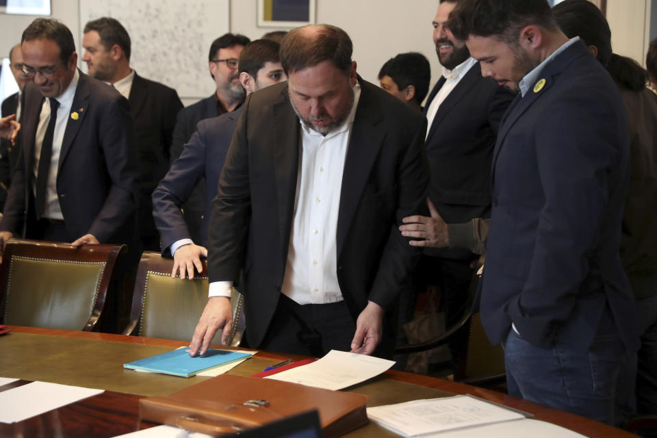 The leader of the Catalonian ERC party Oriol Junqueras, centre, prepares to sign some documents and collect his credentials alongside the ERC parliamentary spokesperson Gabriel Rufian, right, inside the Spanish parliament in Madrid, Spain, Monday May 20, 2019. The five separatist leaders on trial for Catalonia's 2017 secession attempt who were elected to the Spanish Parliament in April 28 elections have been escorted by police to pick up their official parliament credentials. The Supreme Court is allowing the five politicians to get their credentials on Monday and attend the opening session of the new Parliament on Tuesday. (J.J. Guillen/Pool Photo via AP)