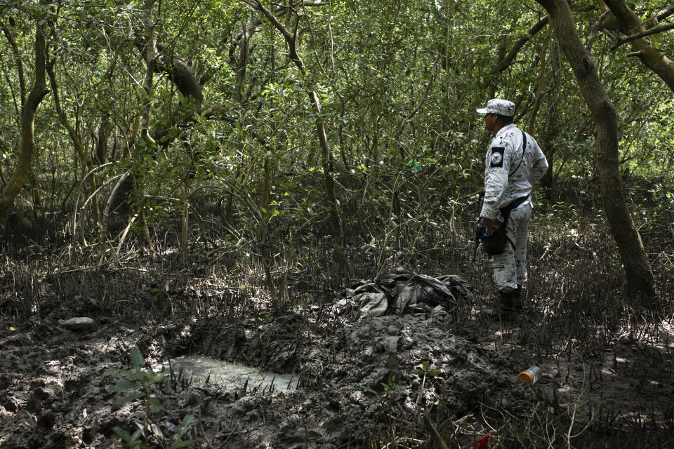 A member of the National Guard stands next to a clandestine grave in Puquita, a tropical mangrove island near Alvarado in the Gulf coast state of Veracruz, Mexico, Thursday, Feb. 18, 2021. Investigators from the National Search Commission found three pits with human remains and plastic bags inside. The number of bodies there has not yet been determined. (AP Photo/Felix Marquez)