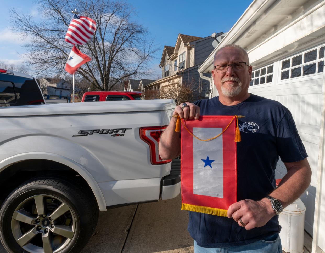 Dewain Divelbliss shows off a blue star service banner at his home in the Pheasant Run neighborhood of Indianapolis, Tuesday, Jan. 17, 2023. Divelbliss’s daughter is a staff sergeant serving in Kosovo, and is part of the Indiana National Guard. 