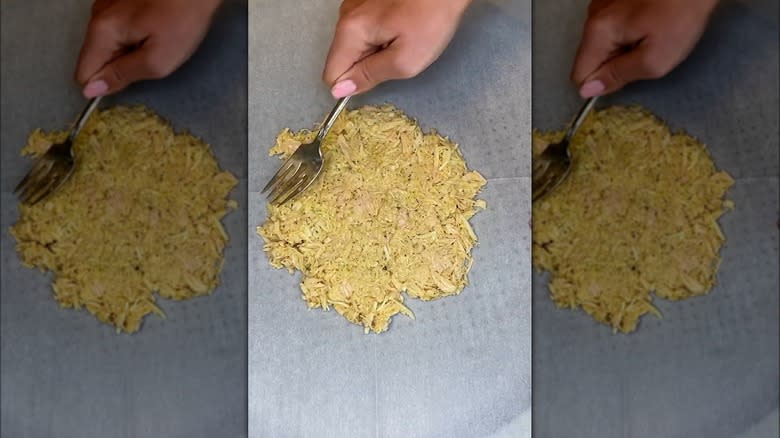 spreading out canned chicken with fork