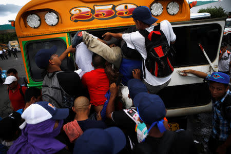 People belonging to a caravan of migrants from El Salvador en route to the United States try to board a bus in Sonsonate, El Salvador, October 28, 2018. REUTERS/Jose Cabezas