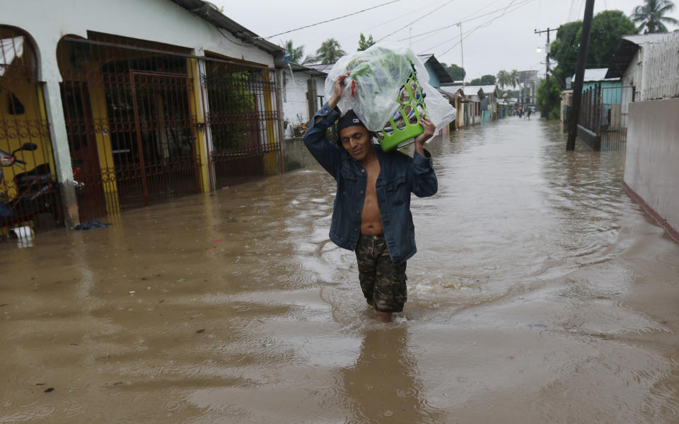 A man walks in knee-deep floodwaters carrying belongings in San Manuel, Honduras, Wednesday, Nov. 4, 2020. Eta weakened from the Category 4 hurricane to a tropical storm after lashing the Caribbean coast for much of Tuesday, its floodwaters isolating already remote communities and setting off deadly landslides. (AP Photo/Delmer Martinez)