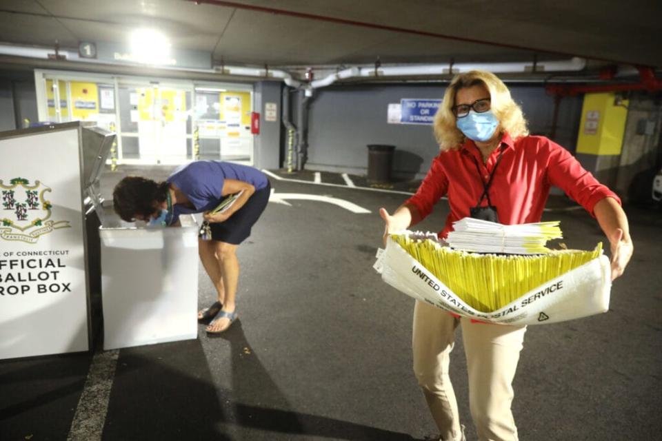 A polling worker carries 2020 presidential primary ballots that were dropped off at a post office and brought to a government center to be processed and counted at the Stamford Government Center on August 11, 2020 in Hartford, Connecticut. (Photo by Spencer Platt/Getty Images)