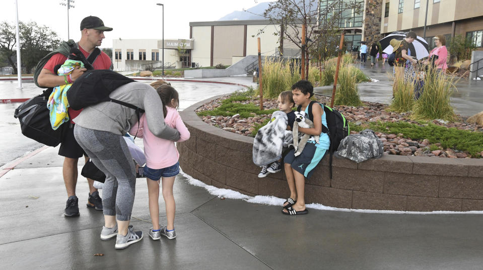 Visitors at the Cheyenne Mountain Zoo were evacuated to Cheyenne Mountain High School and waited to be picked up after a powerful hailstorm storm hit the zoo Monday, Aug. 6, 2018, in Colorado Springs, Colo. Brandon Sneide, left, and his family were caught in the gift shop at the zoo. His son, Gabriel Sneide, clutches a stuffed animal from the zoo while he hugs his brother, Maximus Sneide. Savannah Sneide gets a hug from Sneide's girlfriend, Rebecca Andrews, while they wait for a ride. (Jerilee Bennett/The Gazette via AP)