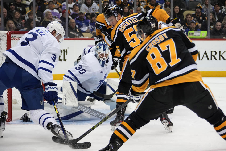 Pittsburgh Penguins' Sidney Crosby (87) tries to get a pass off with Toronto Maple Leafs' Justin Holl (3) defending in front of goaltender Matt Murray (30) during the second period of an NHL hockey game in Pittsburgh, Tuesday, Nov. 15, 2022. (AP Photo/Gene J. Puskar)