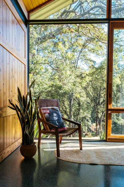 Inside the living room, tall, salvaged-wood-and-glass sliding doors face the neighboring Karura nature preserve. Studio Propolis made the armchair using iroko wood and Kenyan leather.