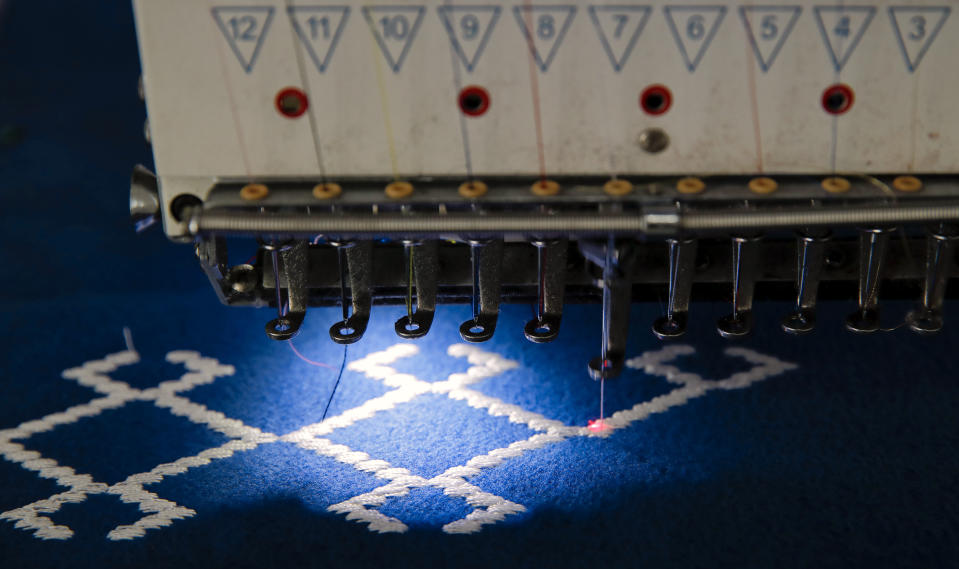 In this picture taken Tuesday, May 21, 2019, an automated sewing machine produces traditional clothing in Luncavita, Romania. Valentina Radu worked in Italy, but when her husband lost his job there, they struggled to pay the rent and decided to come home where they used European Union funds to buy a small farm and she opened a tailor's shop. (AP Photo/Vadim Ghirda)