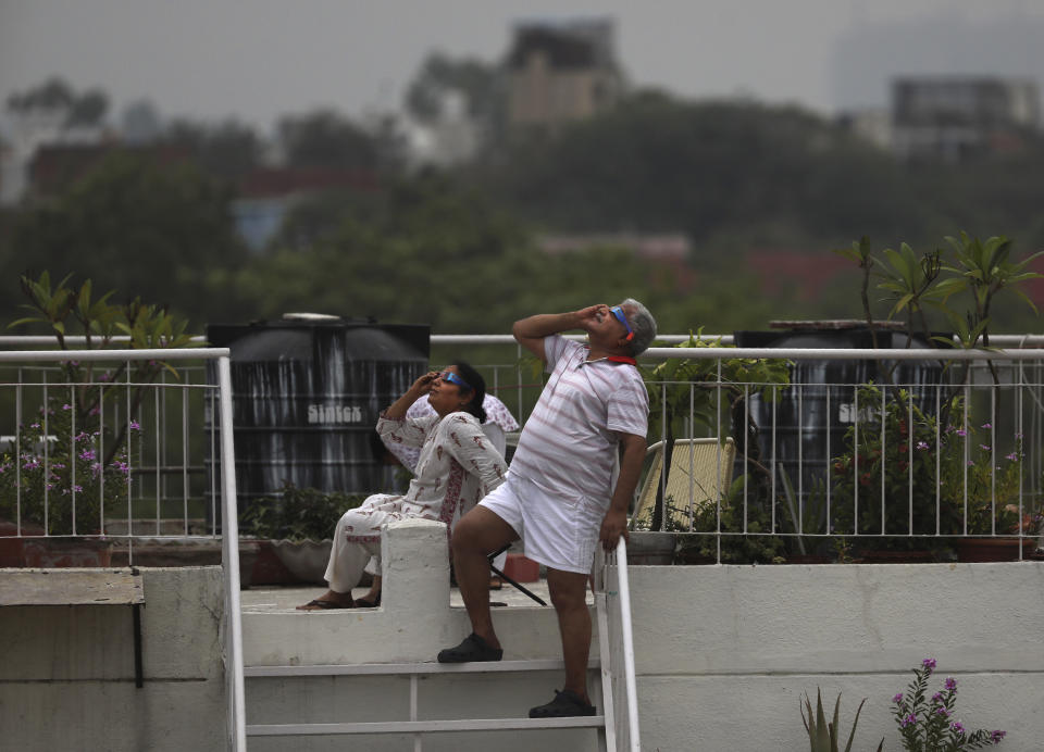 A couple watches solar eclipse from the roof of their house in New Delhi, India, Sunday, June 21, 2020. (AP Photo/Manish Swarup)