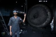 A labourer stands next to a reactor at a pyrolysis unit in Jokhabad