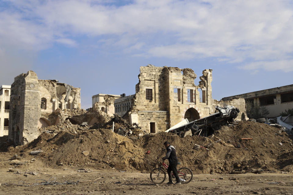 A Palestinian man walks by the remains of destroyed buildings following the Israeli bombardment on the main road of Gaza City on Tuesday, Jan. 2, 2024. (AP Photo/Mohammed Hajjar)