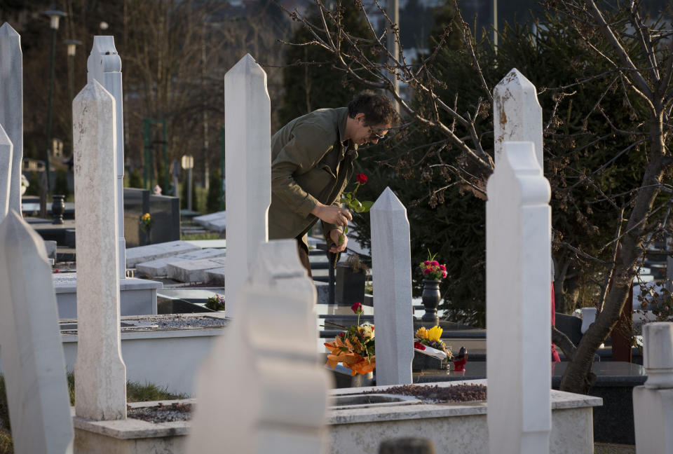 In this Sunday, March 17, 2019 photo, a man places flowers at the section of a cemetery for 1990s war victims in Sarajevo, Bosnia-Herzegovina. Nearly a quarter of a century since Bosnia's devastating war ended, former Bosnian Serb leader Radovan Karadzic is set to hear the final judgment on whether he can be held criminally responsible for unleashing a wave of murder and mistreatment by his administration's forces. United Nations appeals judges on Wednesday March 20, 2019 will decide whether to uphold or overturn Karadzic's 2016 convictions for genocide, crimes against humanity and war crimes and his 40-year sentence. (AP Photo/Darko Bandic)