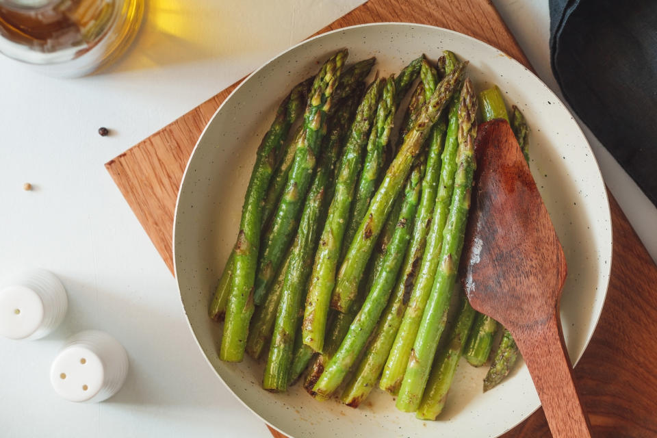 Top view of roasted asparagus in a white pan on a kitchen table