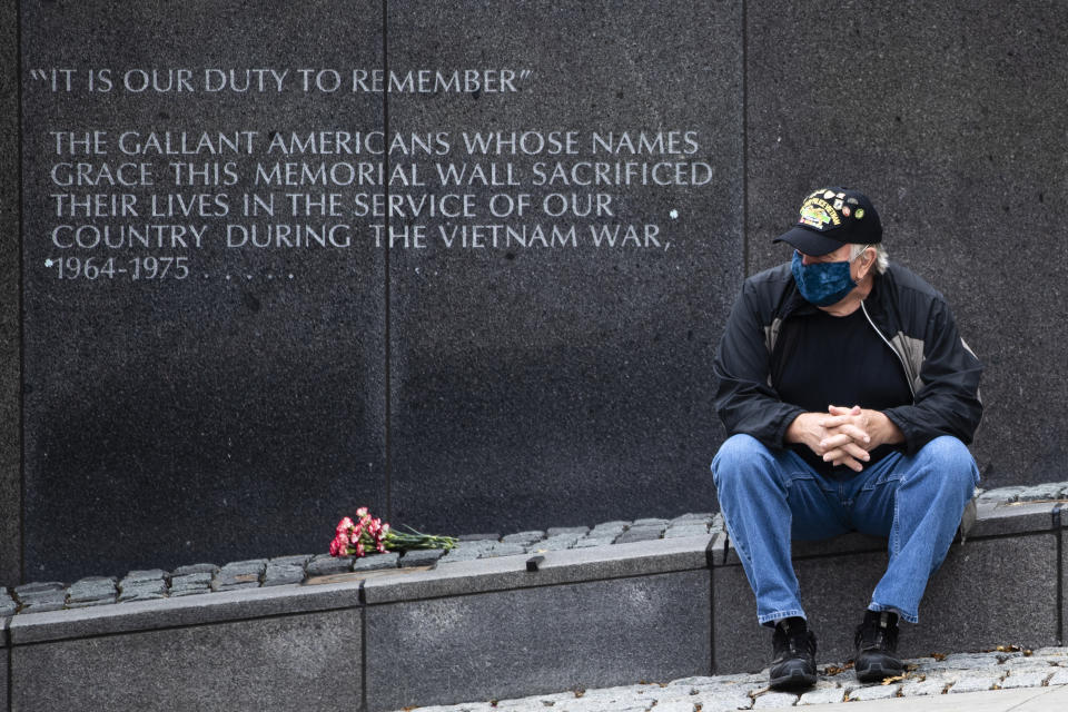 Vietnam Veteran Kitch Kichula, wearing a protective face mask as a precaution against the coronavirus, pays his respects at the at the Vietnam War Memorial, in Philadelphia, on Memorial Day, Monday, May 25, 2020. (AP Photo/Matt Rourke)