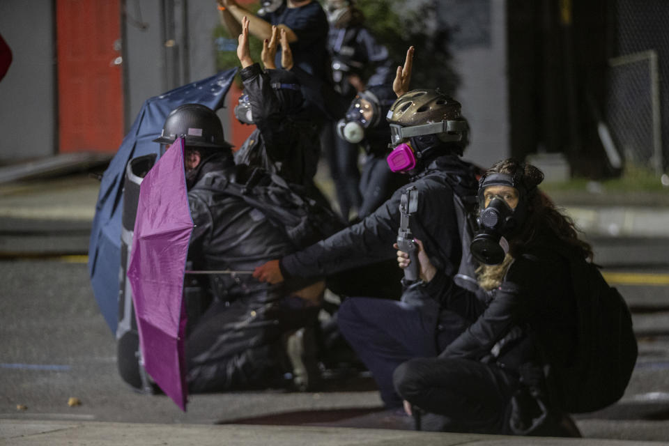 Protesters gather outside the U.S. Immigration and Customs Enforcement office inPortland, Ore., Thursday, Aug. 20, 2020. Portland police say people in a group of about 100 late Thursday and early Friday sprayed the building with graffiti, hurled rocks and bottles at agents and shined laser lights at them. (Mark Graves /The Oregonian via AP)