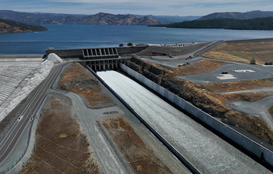 A dam spillway with a full reservoir behind it.