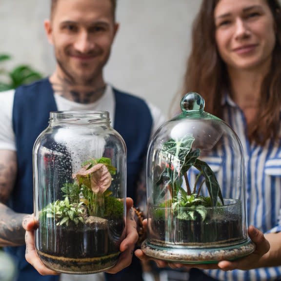  A smiling man and woman hold terrariums. 